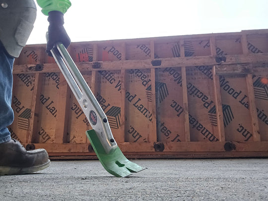 Person using a tool on a concrete surface with a wooden pallet in the background