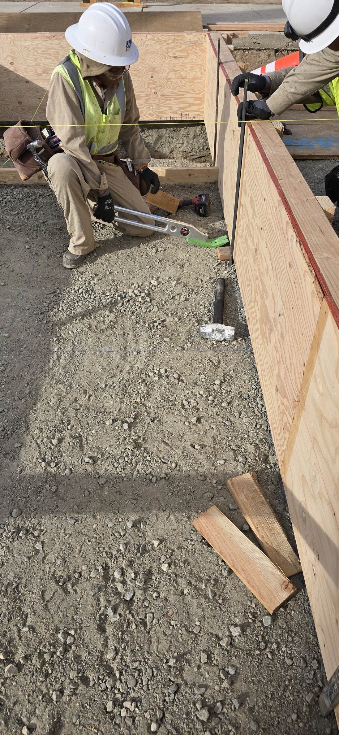 Construction workers working on a concrete foundation with wooden forms.