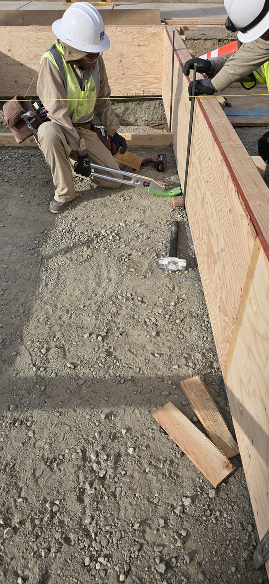 Construction workers working on a concrete foundation with wooden forms.