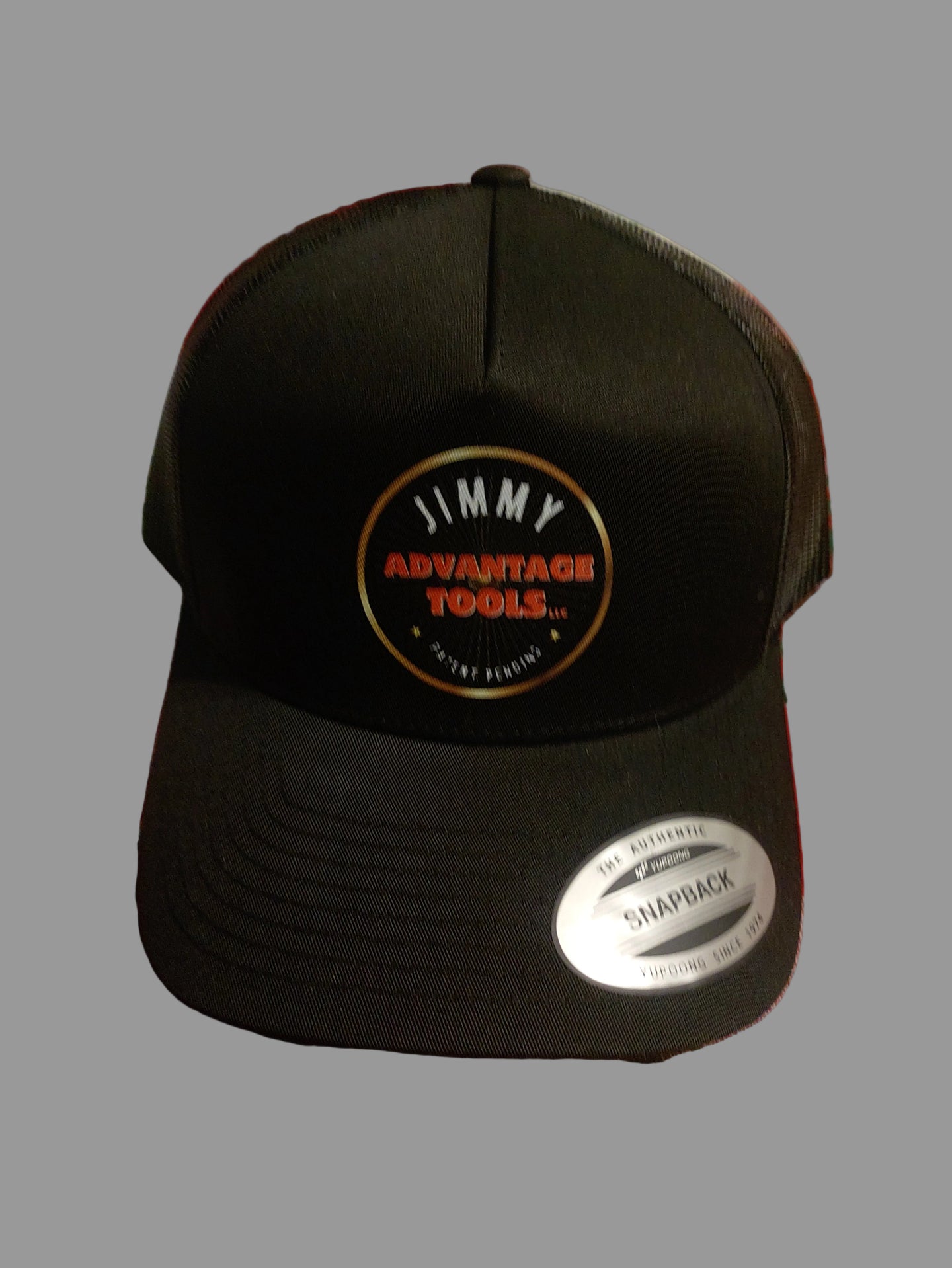 Black cap with a logo on a red and green checkered tablecloth