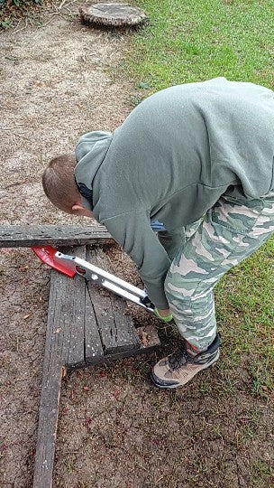 Person using a tool on a wooden bench outdoors